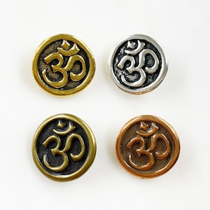 May include: Four metal buttons with the Om symbol in different colors: gold, silver, bronze, and antique brass.