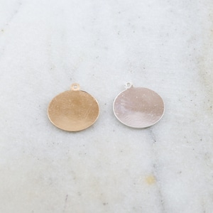 May include: Two round metal charms, one gold and one silver, with a small loop at the top for attaching to jewelry or other crafts.