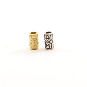 May include: Two decorative hair beads, one gold and one silver, with a swirling pattern.