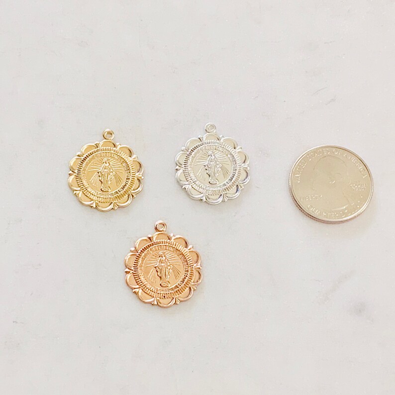 May include: Three gold-toned pendants featuring a religious image of the Virgin Mary. The pendants are approximately the size of a US quarter.