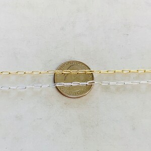 K&ouml;nnte beinhalten: Zwei goldene und silberne Kettenhalsb&auml;nder, die neben einem US-amerikanischen Viertel ausgelegt sind, um die Gr&ouml;&szlig;e zu zeigen. Die Ketten sind beide Boxketten.