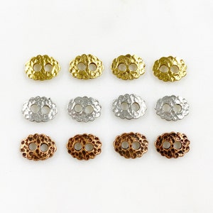 Puede incluir: Doce botones metálicos ovalados con superficie texturizada. Los botones son de tres colores: dorado, plateado y cobre.