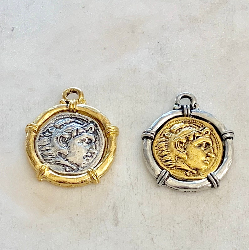 May include: Two round coin pendants, one gold and one silver, with a profile of a person's face on each. The pendants have a rope-like design around the edges.