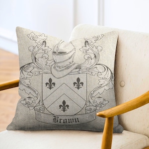 May include: A cream-colored throw pillow with a black and white crest featuring a helmet, shield, and the word "Brown".
