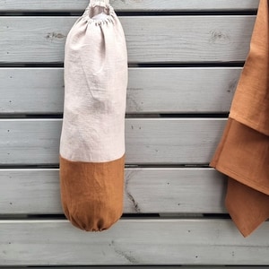 Plastic bag holder made of linen fabric helps to organize plastic bags for reuse. Can be used as a grocery bag holder, kitchen bag storage, bag dispenser. Has a loop for hanging. The hole on top for inserting bag, the bottom hole to take it for using