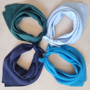 Könnte beinhalten: Vier Stoffbandanas in verschiedenen Farben: Türkis, Hellblau, Dunkelblau und Türkis. Die Bandanas sind in einem Kreis angeordnet, wobei das türkisfarbene Bandana oben liegt.