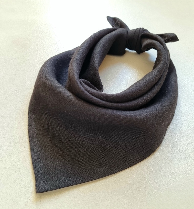 May include: A black bandana made of a soft, textured fabric. The bandana is folded into a triangle shape and tied at the top.