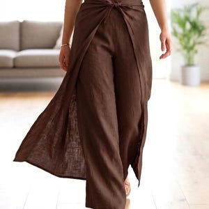 Può includere: Pantaloni a vita alta marrone scuro caratterizzati da un pannello frontale a portafoglio che si annoda in vita con una cintura in tessuto abbinata. I pantaloni a gamba larga hanno una silhouette fluida e sono abbinati a un semplice top nero senza maniche.