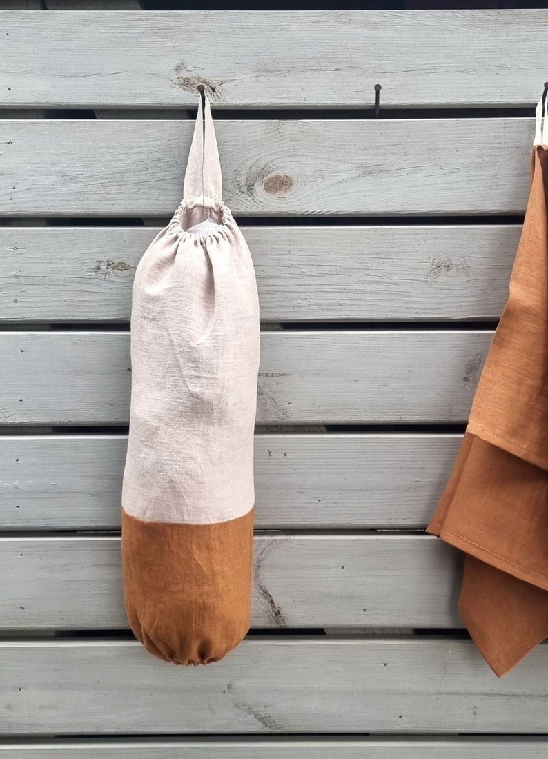 Plastic bag holder made of linen fabric helps to organize plastic bags for reuse. Can be used as a grocery bag holder, kitchen bag storage, bag dispenser. Has a loop for hanging. The hole on top for inserting bag, the bottom hole to take it for using
