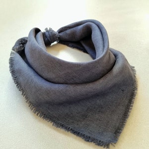 May include: A dark gray bandana with a frayed edge. The bandana is folded in a triangular shape.