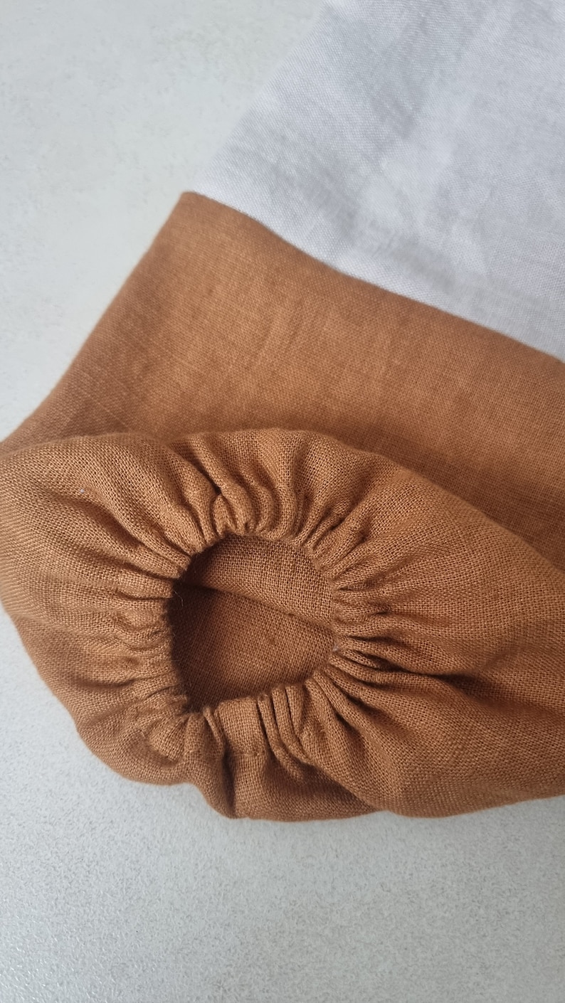 May include: A brown linen fabric with a gathered elastic band. The fabric is a light brown color and has a soft, textured feel.