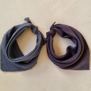 May include: Two dark gray fabric bandanas with frayed edges. One bandana is folded in half and the other is tied in a knot.