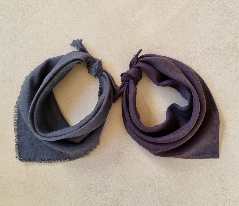 May include: Two dark gray fabric bandanas with frayed edges. One bandana is folded in half and the other is tied in a knot.