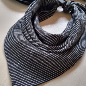 May include: A black and white striped bandana with a knotted design. The bandana is made of a soft, textured fabric.