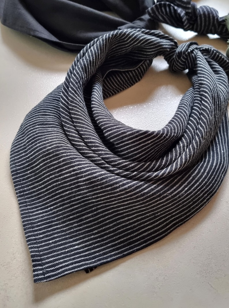 May include: A black and white striped bandana with a knotted design. The bandana is made of a soft, textured fabric.
