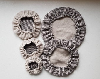 May include: Set of four beige and brown striped fabric bowl covers. The covers are made of linen and have a gathered edge. The covers are arranged in a size order from largest to smallest.