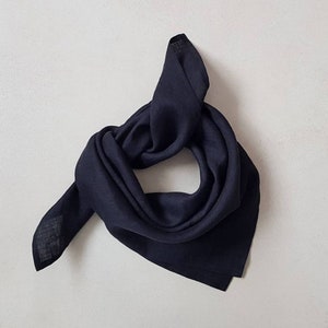 May include: A dark blue linen bandana folded into a triangle shape. The bandana is made of a soft, lightweight fabric and is perfect for adding a touch of style to any outfit.