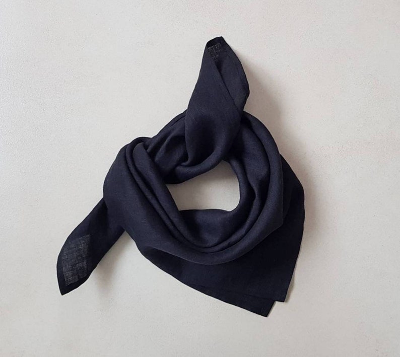 May include: A dark blue linen bandana folded into a triangle shape. The bandana is made of a soft, lightweight fabric and is perfect for adding a touch of style to any outfit.