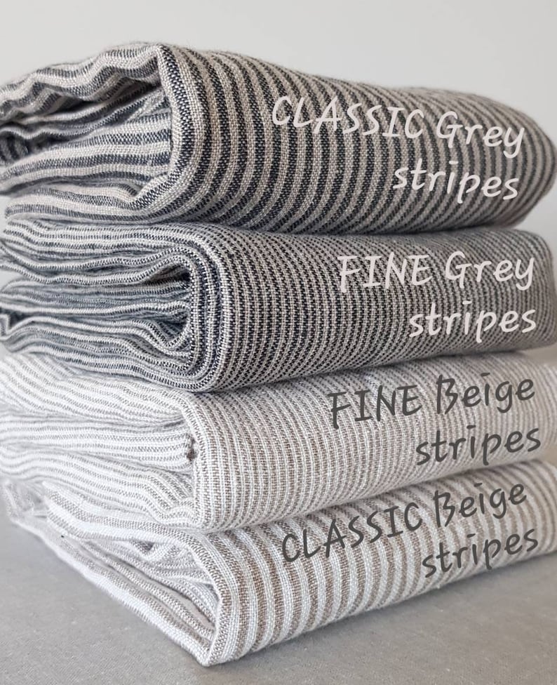 May include: Four different striped fabric swatches stacked on top of each other. The top swatch is a classic grey stripe, the second is a fine grey stripe, the third is a fine beige stripe, and the bottom swatch is a classic beige stripe.