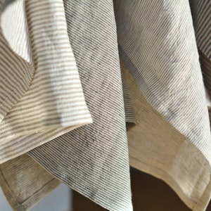 May include: Four striped fabric towels hanging in a row. The towels are in shades of beige, gray, and white.