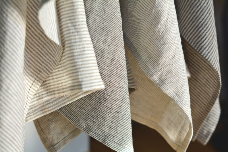 May include: Four striped fabric towels hanging in a row. The towels are in shades of beige, gray, and white.