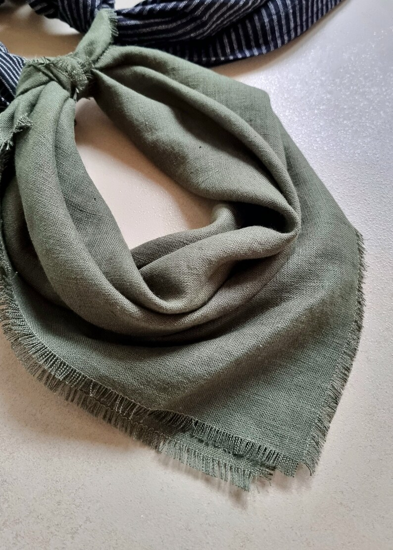 May include: A green bandana with frayed edges. The bandana is folded and tied in a knot.