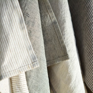 May include: A set of four striped fabric tea towels in various shades of brown, white, and gray. The towels are folded and hanging together.