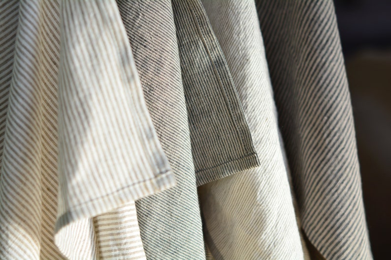 May include: A set of four striped fabric tea towels in various shades of brown, white, and gray. The towels are folded and hanging together.
