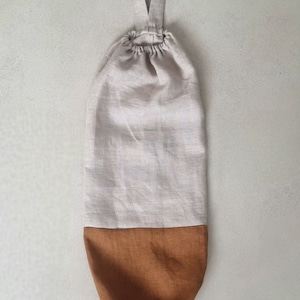 May include: A beige and brown linen reusable grocery bag with a single loop handle.