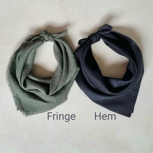May include: Two fabric bandanas, one green with a fringed edge and one black with a hemmed edge. The bandanas are laid flat on a light gray surface. The words "Fringe" and "Hem" are written below the bandanas.