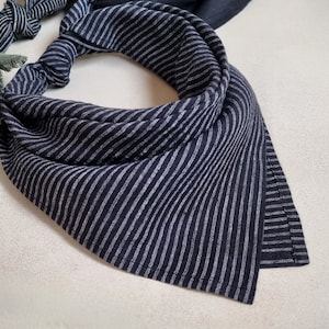 May include: A black and white striped bandana with a frayed edge. The bandana is made of a soft, lightweight fabric.