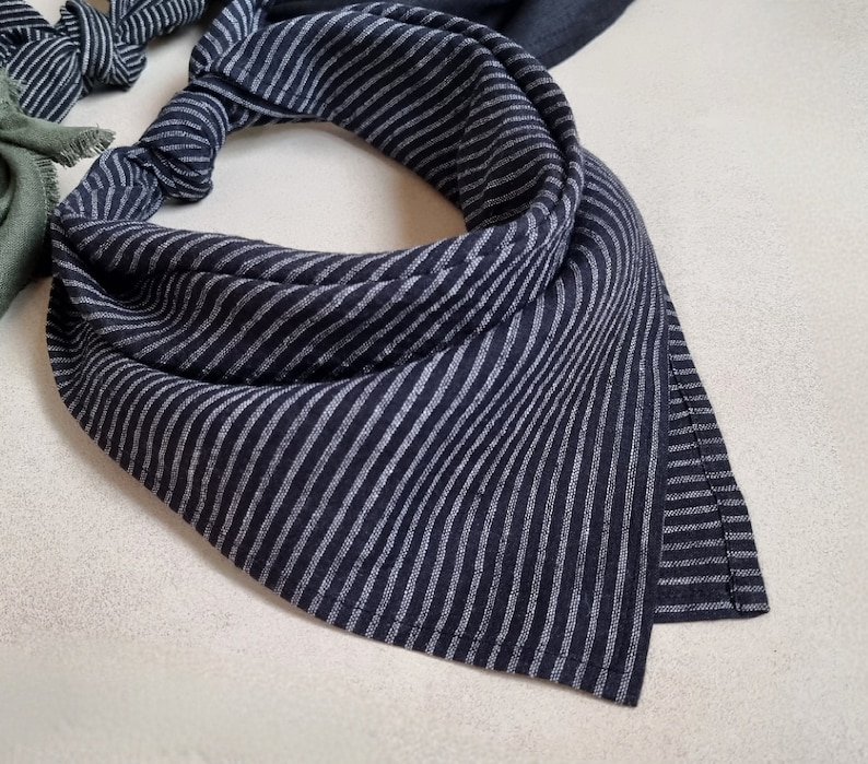 May include: A black and white striped bandana with a frayed edge. The bandana is made of a soft, lightweight fabric.