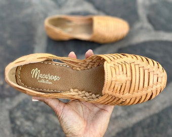 May include: Tan leather sandals with a woven design. The sandals have a leather insole with the text "Macarena collection" printed on it.