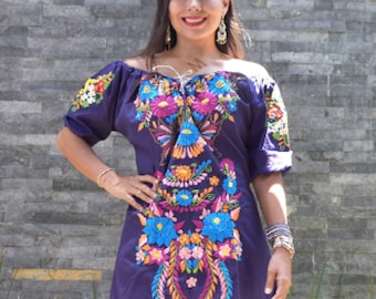 May include: A purple embroidered dress with colorful floral designs. The dress has a square neckline and short sleeves.