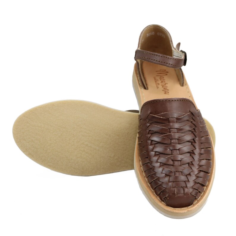 May include: Brown leather sandal with a woven design on the top. The sandal has a light-coloured sole and an ankle strap with a buckle. The sole measures approximately 24 cm in length.