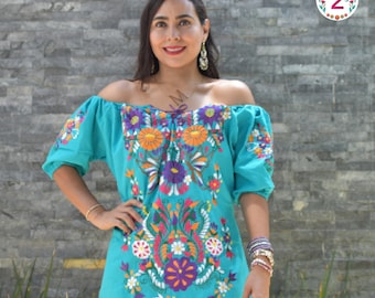 Könnte beinhalten: Ein türkisfarbenes, schulterfreies, besticktes Kleid mit bunten Blumenmustern. Das Kleid hat einen gerafften Ausschnitt und kurze Puffärmel.