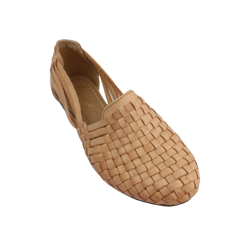 Puede incluir: Sandalias planas de cuero trenzado de color beige con un dise&ntilde;o recortado.