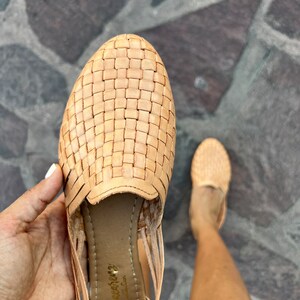 Puede incluir: Sandalias de cuero color canela con un dise&ntilde;o tejido. Las sandalias tienen una correa que va alrededor del tobillo y una peque&ntilde;a abertura en la punta. Las sandalias est&aacute;n hechas por la marca "Huichol" y tienen una suela de cuero.