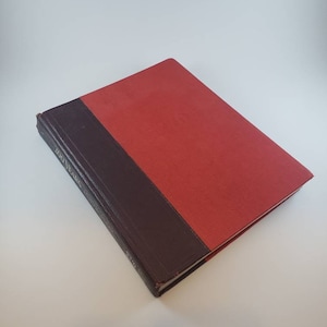 May include: A red hardcover book with a dark brown spine. The book title is "The Stars" and the author is "James"