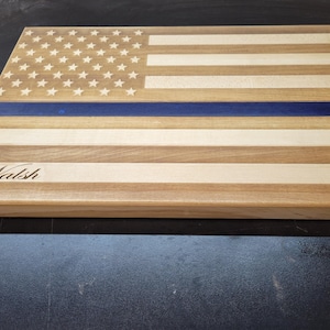 May include: Wooden cutting board with an American flag design and a blue line, personalized with the name "Walsh".