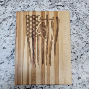May include: A wooden cutting board with a distressed American flag design. The flag is burned into the wood, creating a rustic look.
