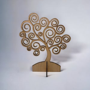 May include: A wooden tree sculpture with a detailed design. The tree features a trunk and branches with swirling, circular leaves. The sculpture is made of light brown wood and stands on a small base with a support stand.