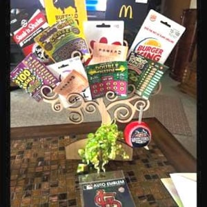 May include: A decorative arrangement featuring gift cards from various restaurants and businesses, including Burger King and McDonald's. The arrangement also includes lottery tickets and a St. Louis Cardinals auto emblem.