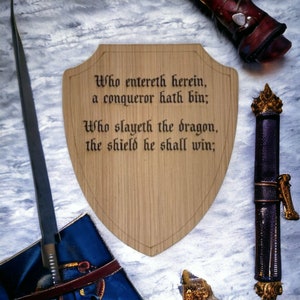 May include: A wooden shield with a carved inscription: "Who entereth herein, a conqueror hath bin; Who slayeth the dragon, the shield he shall win;"