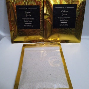 May include: Two gold foil pouches with a white powder inside. The pouches have black labels that read "Ms. G's Curious Goods Destruction Powder Satchet Powder NET WT. 1 OZ (28g)"