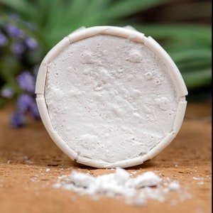 May include: A white round deodorant stick with a textured surface. The deodorant is on a brown surface.