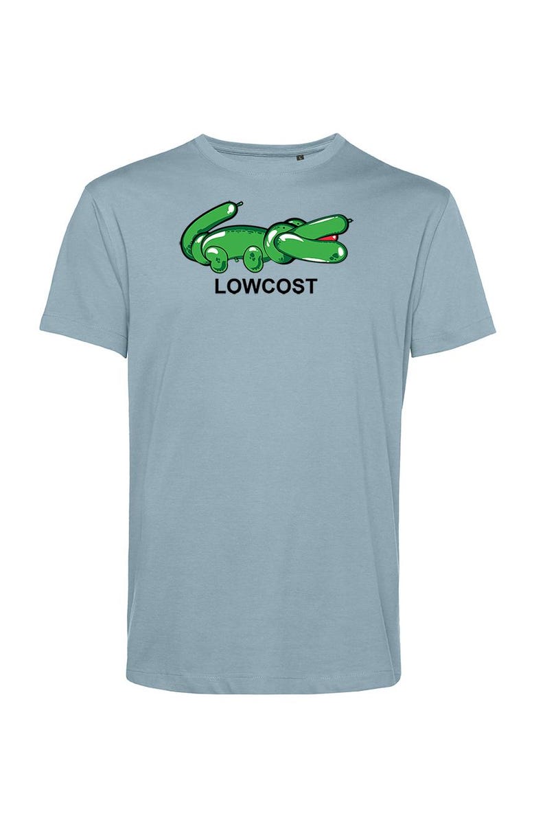 May include: Light blue t-shirt featuring a green cartoon alligator design with the word "LOWCOST" printed below. The alligator has a red mouth and is made to look like a balloon animal. The shirt is a short-sleeved crew neck.