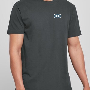 Op de afbeelding: Donkergrijs T-shirt met een klein wit en blauw Schots vlagembleem op de linkerborst. De top heeft korte mouwen en een ronde hals. De stof lijkt een zachte katoenmix te zijn.