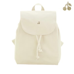Könnte beinhalten: Ein cremefarbener Rucksack aus Segeltuch mit einer oberen Klappe, die mit einer kleinen goldenen Glitzer-Kirschgrafik verziert ist. Die Tasche hat einen Kordelzug mit zwei geknoteten Enden und einen Tragegriff. Ein größeres Kirschsymbol ist oben rechts.