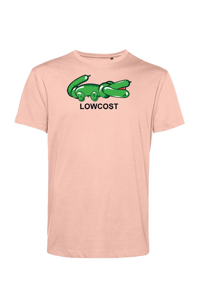 May include: A light pink t-shirt featuring a green cartoon alligator design with the word "LOWCOST" in black text. The alligator has a red mouth and is in a relaxed pose. The shirt has short sleeves.